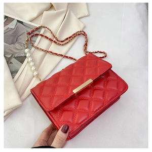 Détail du mini sac matelassé rouge avec fermoir doré et bandoulière en perles blanches