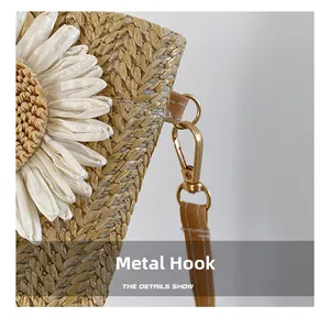 Dettaglio macro della borsa in paglia con decoro floreale e gancio in metallo