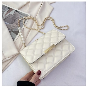 Détail du sac matelassé crème avec bandoulière en perles et fermoir doré sur fond soie