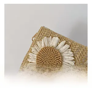 Dettaglio borsa in paglia intrecciata a mano con margherita bianca 3D e tracolla in pelle