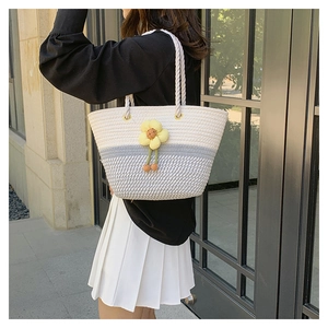 Détail du sac cabas tissé bicolore blanc et gris avec breloque fleur jaune