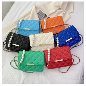 Détail de sacs bandoulière matelassés avec chaînes en perles en sept couleurs vives