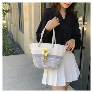 Détail du sac cabas tissé gris et blanc avec fleur 3D jaune et anses en corde épaisse