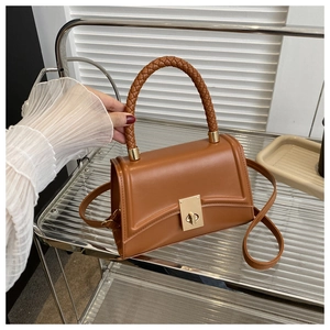 Detail of a brown leather handbag featuring a woven handle and golden rectangular lock