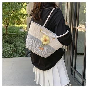 Gros plan du sac cabas tissé avec rayures gris blanc et décoration de fleur jaune