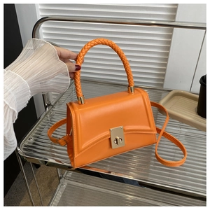 Detail of orange hourglass handbag with woven handle and gold twist-lock closure