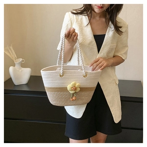 Détail d'un sac seau tricoté bicolore avec pendentif fleur et anse en corde tressée