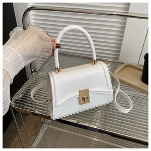 Detail of the white PU leather handbag featuring a woven handle and gold twist lock clasp