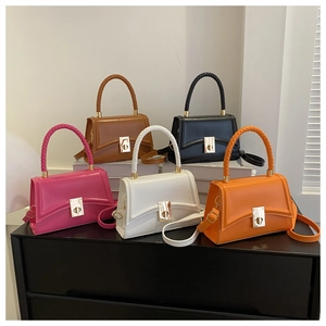 Five small crossbody bags in various colors on display with woven handles and metal locks