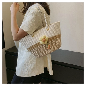 Vue portée du sac cabas tissé avec couleurs contrastées et breloque fleur jaune en tricot