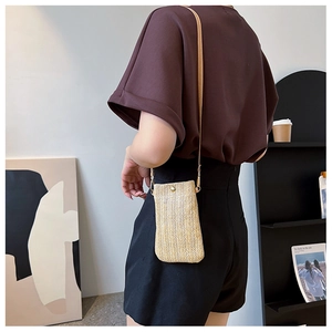 Dettaglio borsa porta cellulare in paglia intrecciata con fibbia dorata e tracolla in pelle