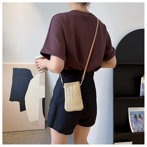 Dettaglio della trama in paglia intrecciata e tracolla in pelle marrone della mini borsa