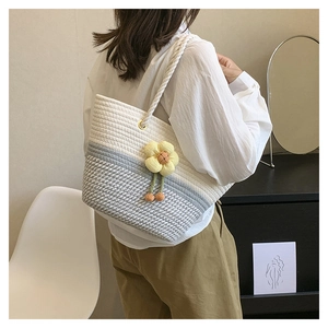 Détail du sac cabas tissé avec rayures grises et breloque fleur en peluche jaune