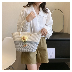 Détail de la poignée en corde tissée et de la fleur 3D sur le sac seau en paille