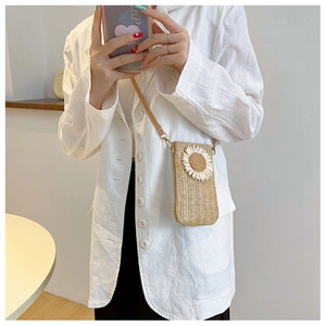 Dettaglio borsa porta cellulare in paglia intrecciata con margherita su blazer bianco