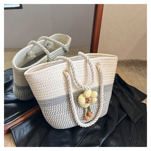 Vue détaillée du sac seau tissé en corde de coton bicolore avec un pendentif fleur jaune