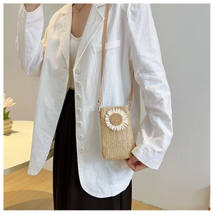 Dettaglio della borsa in paglia intrecciata con girasole bianco e tracolla sottile