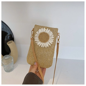 Dettaglio della borsa porta cellulare in paglia intrecciata con margherita bianca e tracolla