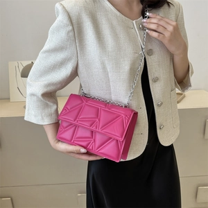 Hot pink quilted crossbody bag with silver chain strap worn by a female model