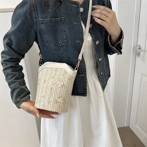 Woven bucket bag in cream with green floral embroidery and adjustable leather strap