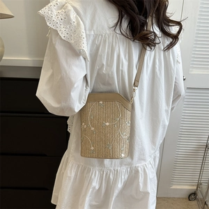 Woven straw bucket bag with floral embroidery and brown leather strap for women