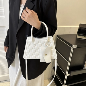 Quilted white trapezoid handbag with embossed pattern and matching mini envelope pouch