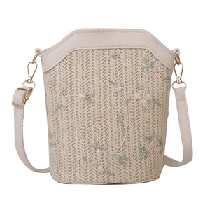 Fashion woven straw bucket bag with floral embroidery and adjustable strap on white background