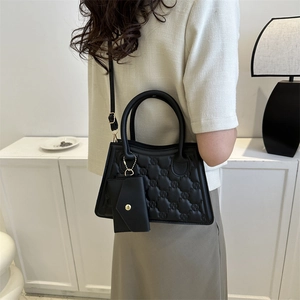 Chic black quilted handbag with monogram embossing and a matching mini pouch charm