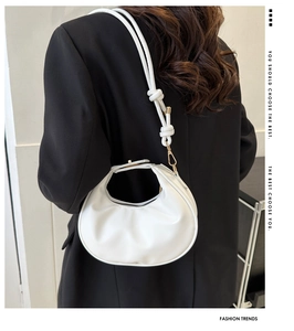 Détail du sac croissant blanc avec bandoulière à nœud élégante et finitions dorées
