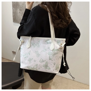 Detail of white tote bag with green butterfly prints and drawstring side design