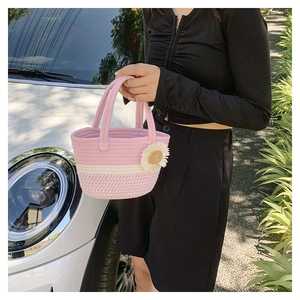 Detail of pink and white woven cotton bucket bag with a white daisy floral charm