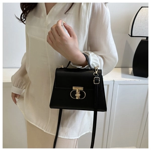 Close-up of black leather handbag featuring a golden T-shaped metal twist lock closure