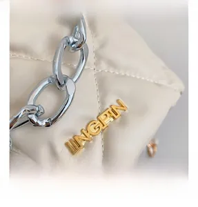 Detailed close-up of quilted beige leather texture and gold metal JINGPIN logo on handbag