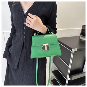 Close-up of green leather crossbody bag with iconic gold T-shaped lock on black garment
