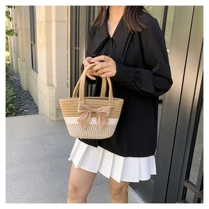 Detail of hand-woven basket bag with decorative bow and textured two-tone strap
