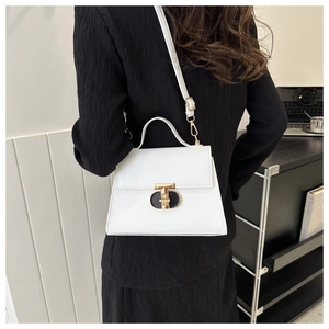 Borsa a mano bianca minimalista con fibbia a T dorata indossata a spalla da donna
