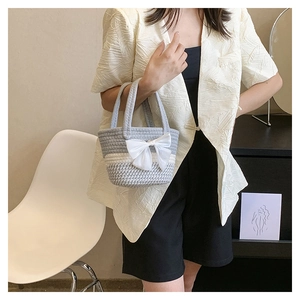 Detail of hand-crocheted striped bucket bag with silk bow and gray-white pattern
