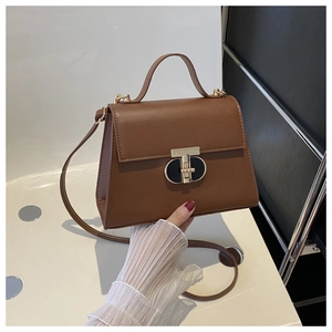 Detail of dark brown leather crossbody bag featuring a stylish gold and black T-lock closure