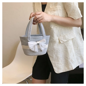 Detail of hand-woven bucket bag with grey block design and large white chiffon bow decor