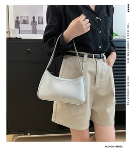 Minimalist white leather baguette bag styled with a modern outfit in a natural studio setting
