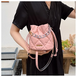 Detail of pink quilted bucket bag showing mixed-tone chain handle and drawstring closure