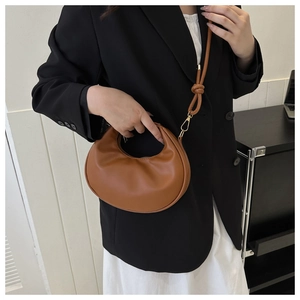 Vue détaillée du sac croissant marron avec poignée et bandoulière ornée d'un détail de nœud