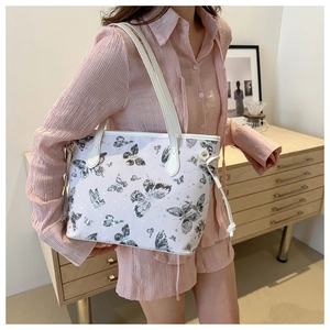 Close-up of stylish white tote bag featuring grey butterfly print and side tassel details