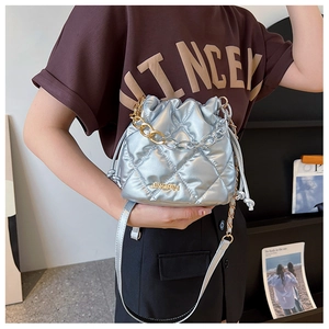 Close-up of quilted silver bucket bag with gold chain strap and drawstring closure
