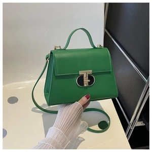 Close-up of green leather handbag featuring a golden T-shaped metal twist lock and top handle