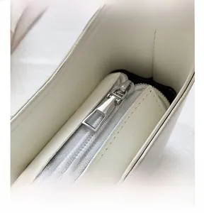 Detailed close-up of smooth silver zipper and stitching on a white leather handbag