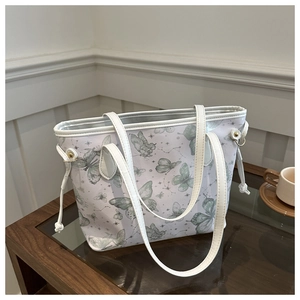 Detail of white tote bag with green butterfly print and decorative side drawstring