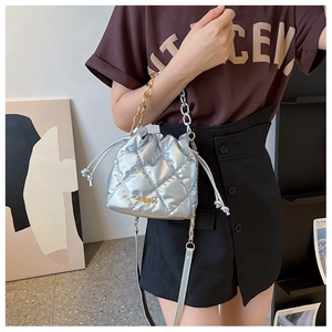 Detail of silver quilted bucket bag with chain handle shown on a model