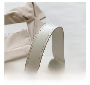Close-up of reinforced stitching and fine leather texture on white shoulder bag strap