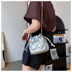 Close-up of silver quilted bucket bag with metal chain strap and drawstring closure